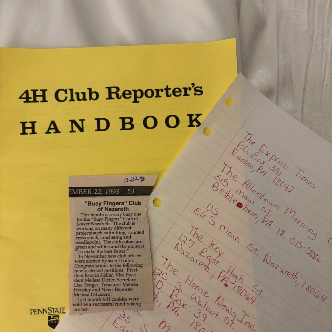 A yellow 4‑H Club Reporter’s Handbook laid out with a handwritten red‑ink media contact list and a newspaper clipping from a 1993 4‑H club article. Vintage documents showing an early start in storytelling and community reporting.